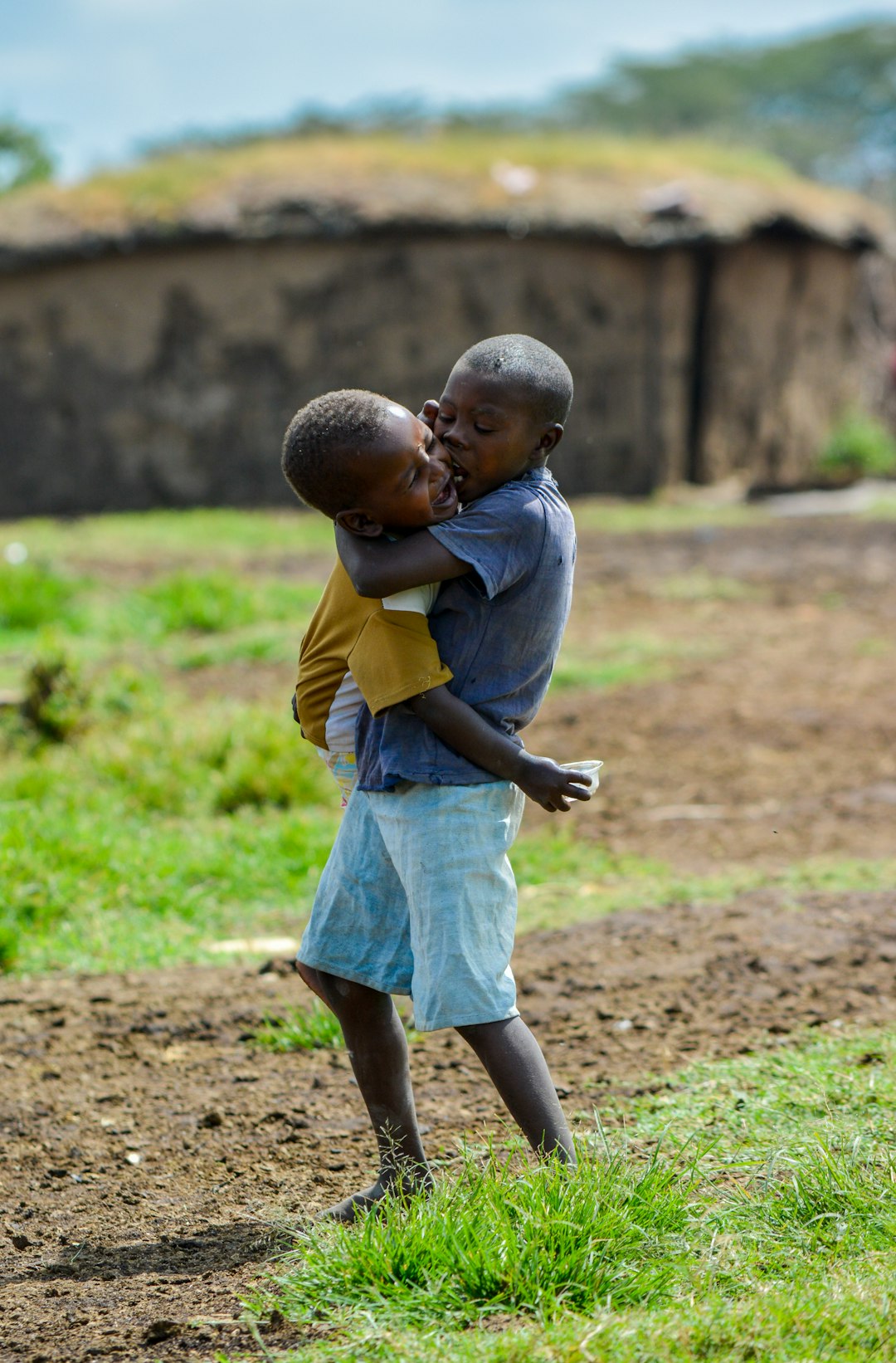 boy-in-grey-t-shirt-holding-child-at-open-field-sm1yfmwseqy